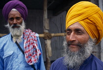 India, Delhi, Portrait of two Sikh men  one standing slightly behind the other with thick grey beards and wearing orange and purple turbans.