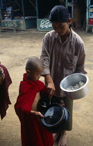 Myanmar, Kyaiktiyo, Novice monk receiving alms.