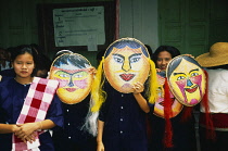 Thailand, Sukhothai, Si Satchanalai, Girls wearing large painted masks to celebrate novice monks.