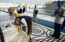 India, Punjab, Amritsar , Golden Temple. Sikh pilgrims praying at shrine with sacred pool and temple behind.
