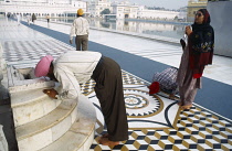 India, Punjab, Amritsar, Golden Temple. Sikh pilgrims praying at shrine.