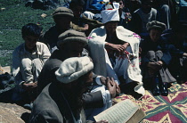 Pakistan, Religion, Wedding, Shani village wedding with bridegroom dressed in embroidered white robe and head-dress sitting amongst boys and men.