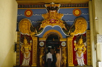 Sri Lanka, Kandy, Temple of the Tooth. Family at temple entrance framed by brightly painted carvings.