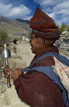 India, Ladakh, Religion, Tibetan Buddhist priest holding prayer wheel.
