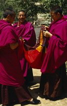 China, Qinghai, Ta er Si, Tibetan monks inspecting lengths of material.