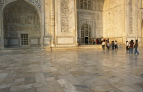 India, Uttar Pradesh, Agra, Partial view of the exterior of the Taj Mahal showing decoration of semi-precious stone inlay using process of pietra dura and Arabic script. Pilgrims and tourists.