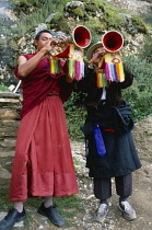 China, Tibet, Lhasa, Drak Yerpa Monastery complex, Monk and layman blowing trumpets with rainbow tassles hanging from them.