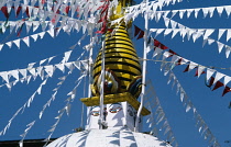 Nepal, Kathmandu Valley, Swayambhunath, Central temple stupa painted with the eyes of Buddha and hung with red and white flags.