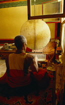 China, Tibet, Shigatse, Monk chanting from Tibetan prayer book in cell in Ta er Si temple also known as Kumbum.