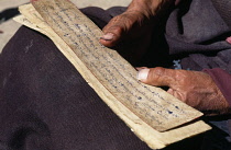 India, Ladakh, Religion, Close cropped shot of monk holding ancient Buddhist texts.