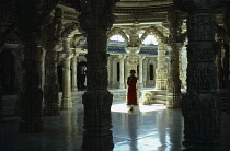 India, Rajasthan, Mount Abu, Interior of Jain temple with elaborately carved roof and supporting pillars framing female visitor.