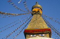 Nepal, Kathmandu Valley, Bodhnath, Detail of Bodhnath stupa hung with prayer flags and showing the painted eyes of Buddha.