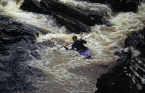 Scotland, Highlands, Kingussie, Man Kayaking at Feshie Bridge over River Feshie.