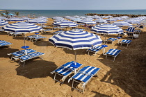 Italy, Sicily, Marina Di Ragusa, Sun umbrellas and sun beds on a beach.