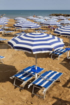 Italy, Sicily, Marina Di Ragusa, Sun umbrellas and sun beds on a beach.