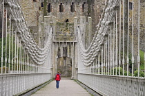 Wales, Conwy, Conwy Suspension Bridge with figure walking towards the walls of Conwy Castle.