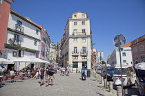 Portugal, Estredmadura, Lisbon, Alfama district, Tourists walking past outdoor cafes.
