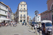 Portugal, Estredmadura, Lisbon, Alfama district, Tourists walking past outdoor cafes.