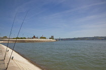 Portugal, Estredmadura, Lisbon, Belem, Torre de Belem built as tower fortress with Memorial and Bridge over river Tagus with fishing rods in the foreground.