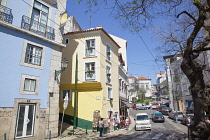 Portugal, Estredmadura, Lisbon, Alfama district, Typical scene with hilly street and traffic on narrow road.