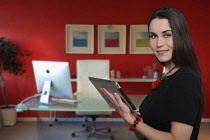 Business, Young woman in smart dress using tablet computer in office setting.