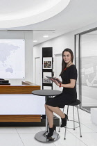 Business, Young woman in smart dress using tablet computer in office setting.