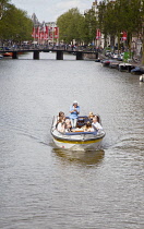 Holland, North, Amsterdam, Tourists on canal tour boats.