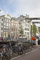 Holland, North, Amsterdam, Bicycles parked next to canal with typical lifting bridge in the background.