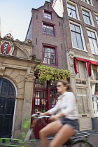 Holland, North, Amsterdam, Typical Dutch gable buildings with blurred girl cyclist.