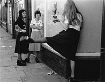 England, Merseyside, Bootle, Young girls in street playing with their reflections in shop window, 1975.