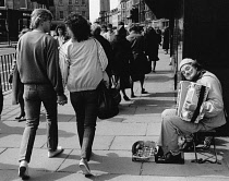 Scotland, Lothian, Edinburgh, Clown busker with young couple holding hands walking by.