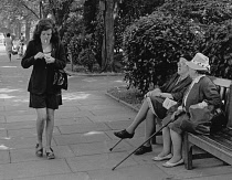 England, Merseyside, Southport, Woman walking along Lord street lighting her cigarette, 1970.