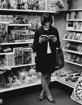 England, Merseyside, Southport, Woman inside W H Smiths store reading.