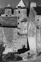 France, Brittany, La Roche Bernard, Silhouetted couple walking down hilly street.