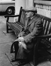 England, Merseyside, Southport, Old man with Pomeranian dog sat on bench on Christmas Eve 1968.