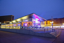 England, Lancashire, Blackpool, Seafront promenade with restaurant illuminated at dusk.