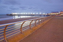 England, Lancashire, Blackpool, Seafront promenade with North Pier illuminated at dusk.