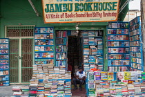 India, Pondicherry, Second-hand bookshop in market with seller using ebook or tablet computer.