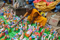 India, Pondicherry, Street vendor arranging a display of nativity figures for sale.