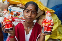 India, Pondicherry, Portait of a girl holding figurines of Father Christmas.