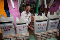India, Pondicherry, Tinker behind a display of metal letter boxes.