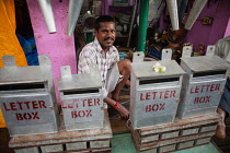 India, Pondicherry, Tinker behind a display of metal letter boxes.