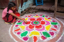 India, Tamil Nadu, Kumbakonam, A girl making a rangoli to celebrate the Pongal festival.