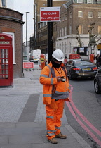 England, London, Workman in high vis and sign for No Idiling.