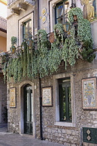Italy, Sicily, Taormina, Ornately decorated house with plants dangling from balcony.