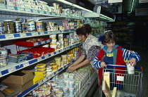 Holland, Supermarket interior with woman and young girl placing food items into trolley.