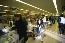 Shopping, Supermarket, Interior of Safeways supermarket in Bearsted, Kent, Shoppers packing trolleys at the checkout with lines of stacked shelves behind.