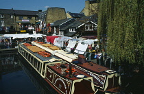 England, London, Camden Lock, Two tourist barges moored at the side of the lock beside a market.