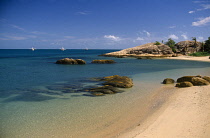 Australia, Queensland, Great Barrier Reef, Plage du Bowen, Sandy beach with large rock boulders next to clear turquoise sea.