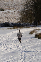 England, Jogger running in field of snow.